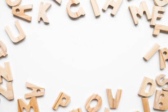 Wooden alphabet letters arranged in circular frame on white background