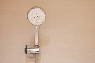 Modern shower fixture in a tiled bathroom, faucet head closeup.
