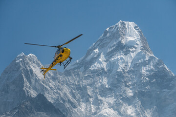 A rescue helicopter is hovering in front of the Ama Dablam mountain in Khumbu, Nepal.