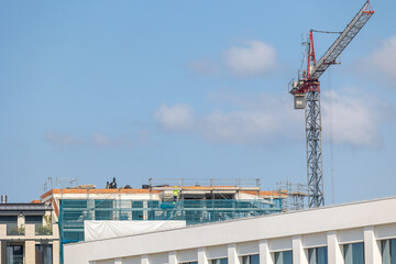 Construction workers building new apartment building with crane on top