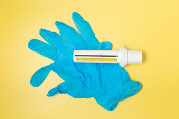 Peak Flow Meter Lying On Blue Gloves On Yellow Background Top View