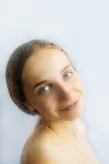Portrait of beautiful and sensual woman captured through wet glass.