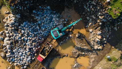 Excavator and dump truck working in rock and sand mine, Construction and mining site view from above.