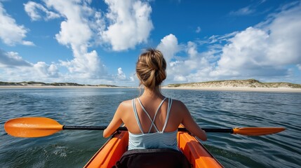 Young female kayaker paddling on serene lake with dramatic sky and sandy shores