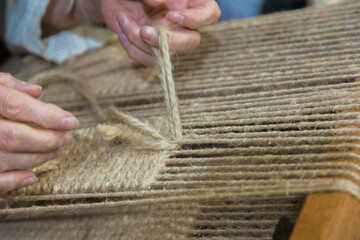 Hands of artisan weaving natural fibers on traditional loom, showcasing craftsmanship and skill