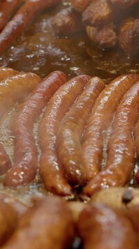 Vertical Screen Delicious sausages sizzling on a hot plate, emitting fragrant steam in a bustling street food market
