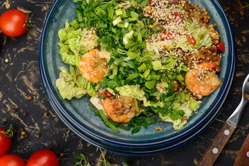 Korean dish with shrimp and greens in a blue plate on a dark background macro