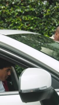 Vertical video: Diverse father guiding teenage son unlocking door in sedan during driving lesson