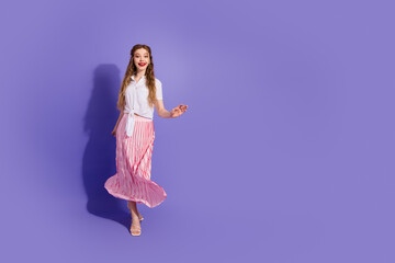 Trendy young woman in stylish summer outfit posing confidently against vibrant purple background conveying charm and elegance
