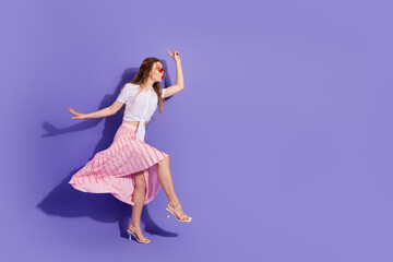 Young woman wearing summer attire posing playfully against a lively purple background, expressing happiness and fashion elegance