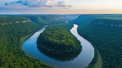 A beautiful aerial view of a winding river flowing through a lush green mountain landscape, with a bright sky in the background.
