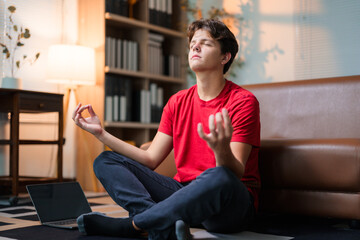 Teenage boy meditating on yoga mat, practicing mindfulness and finding inner calm in sunlit living room