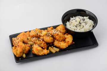 Shrimp tempura in a black plate with rice on a white background