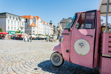 Old vintage European city and pink retro ice cream car. Summer sunny day and travel in Czech Republic, Brno. Pink ice cream truck parked on a sunny square in Brno. Colorful street market and historic