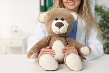 Pediatrician with toy bear at desk in hospital, closeup