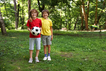 Cute little kids with soccer ball in park, space for text