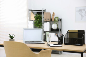 Stylish workplace with laptop and stationery on wooden table in office