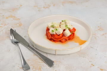appetizer salad with paprika and cheese in a plate macro on a light background with utensils