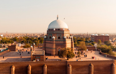 An aerial view of the famous Sufi shrine with a large white dome, surrounded by a walled courtyard...