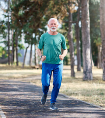 Smiling active mature elderly man jogging running in the park