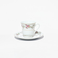 Elegant antique porcelain tea cup and saucer with floral pattern on clean background