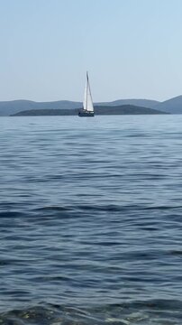 Sailing calmly across tranquil waters near a distant island in clear sunny weather with gentle waves guiding a serene journey