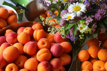 Ripe, juicy apricots in bowls and a bouquet of wildflowers made of daisies, clover, and other flowers