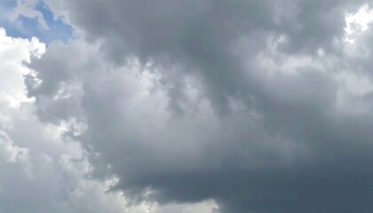 Obraz premium A full frame view of dramatic, gray-and-white clouds with hints of blue, displaying a moody and atmospheric sky.