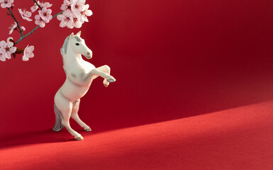 White horse with cherry flowers on a red background, celebration of the Chinese New Year 2026. Year of the horse