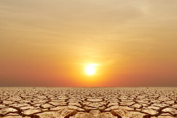 Cracked Earth under the Sunset: The sun casts its final golden rays upon a cracked earth,...