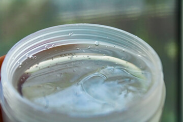 Clear gel with bubbles in jar closeup skincare cosmetic product or Clear glass with fresh water and ice cubes closeup refreshing drink