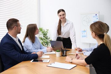 Business coach giving presentation to group of people in office