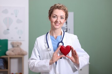 Professional pediatrician with heart model in clinic