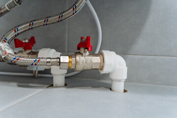 A detailed closeup view of the plumbing system showcasing the various valves and connections located underneath a kitchen sink, highlighting the intricate network of pipes and fittings