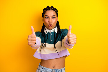Naklejka na ściany i meble Young woman with braids on yellow background showing double thumbs up gesture in a casual trendy outfit