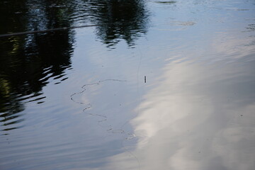 Body of the water of pond or lake, with reflections of the sky and surrounding environment on its surface