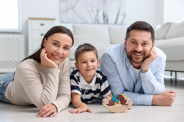 Parents and their son playing with toys on warm floor at home. Heating system