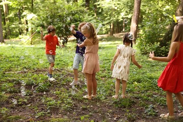Obraz premium Cute little kids having fun with soap bubbles in park