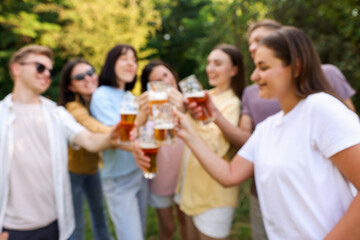 Blurred view of happy friends having fun and drinking beer outdoors