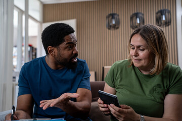 Stressed diverse couple arguing over living costs, rent, and bills at home, worried about expenses and financial problems