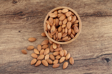 Close up of fresh almonds spilled out of wooden bowl