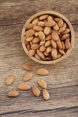 Close up of fresh almonds spilled out of wooden bowl