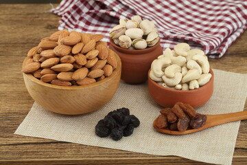 Almonds, pistachios and cashew in wooden bowl and clay pots