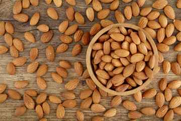 Close up of fresh almonds spilled out of wooden bowl
