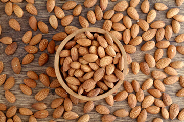 Close up of fresh almonds spilled out of wooden bowl