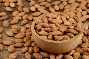 Close up of fresh almonds spilled out of wooden bowl