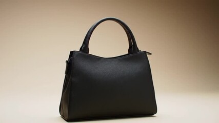 Chic black leather handbag with elegant handles against a soft neutral background