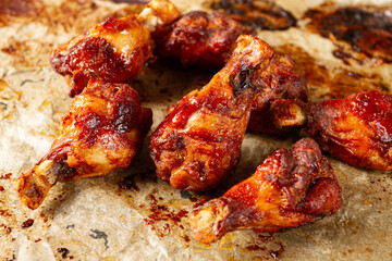 Grilled chicken legs lined with parchment paper and covered with caramelized glaze, close-up,