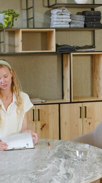 Vertical video: Diverse coworkers presenting tablet, signing contract for approval at meeting table