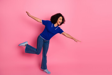 Joyful woman balances playfully on one leg wearing stylish casual attire with a vibrant pink...